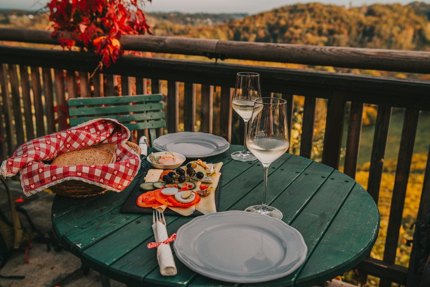 Tagliere di salumi e bicchieri di vino su un tavolo da balcone all'aperto.