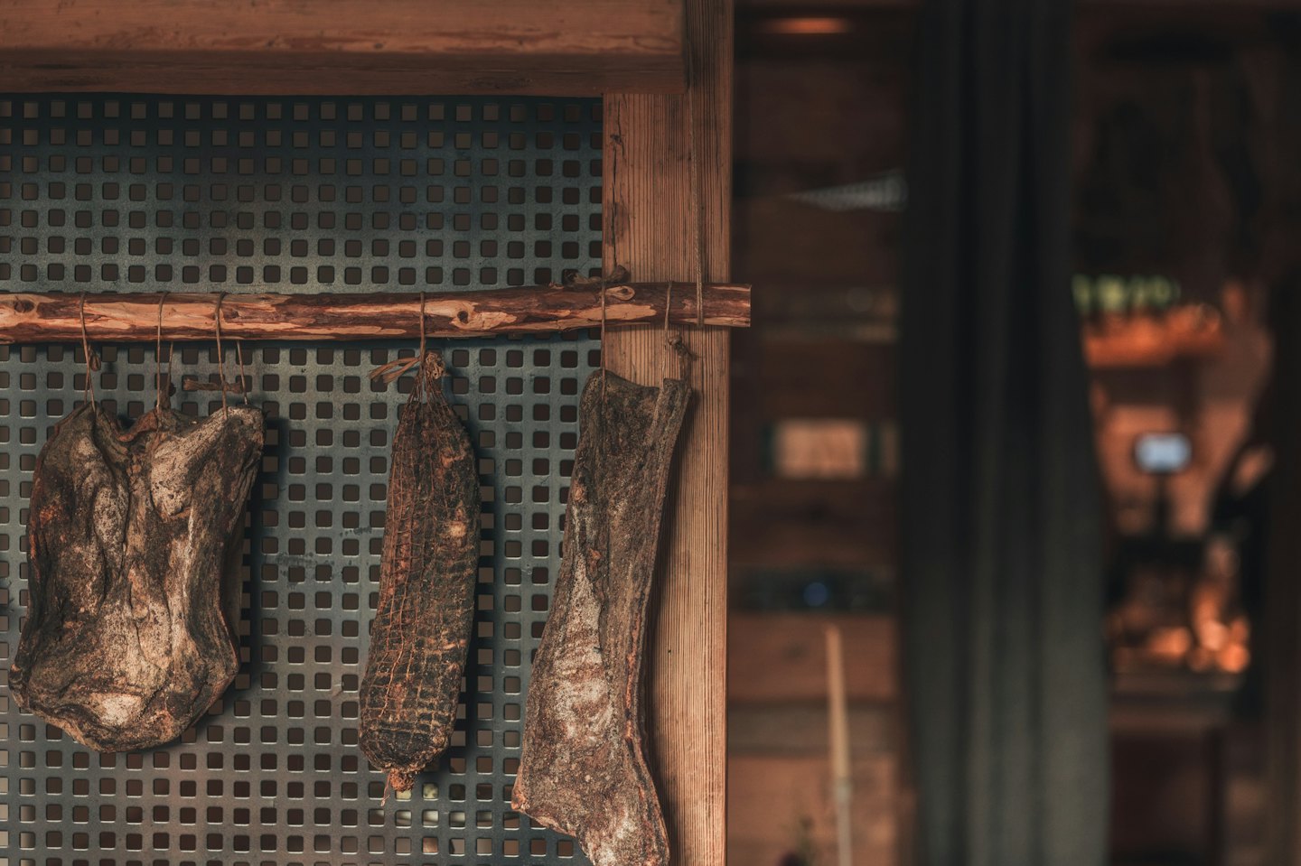 Tre pezzi di salumi appesi a un bastone di legno.
